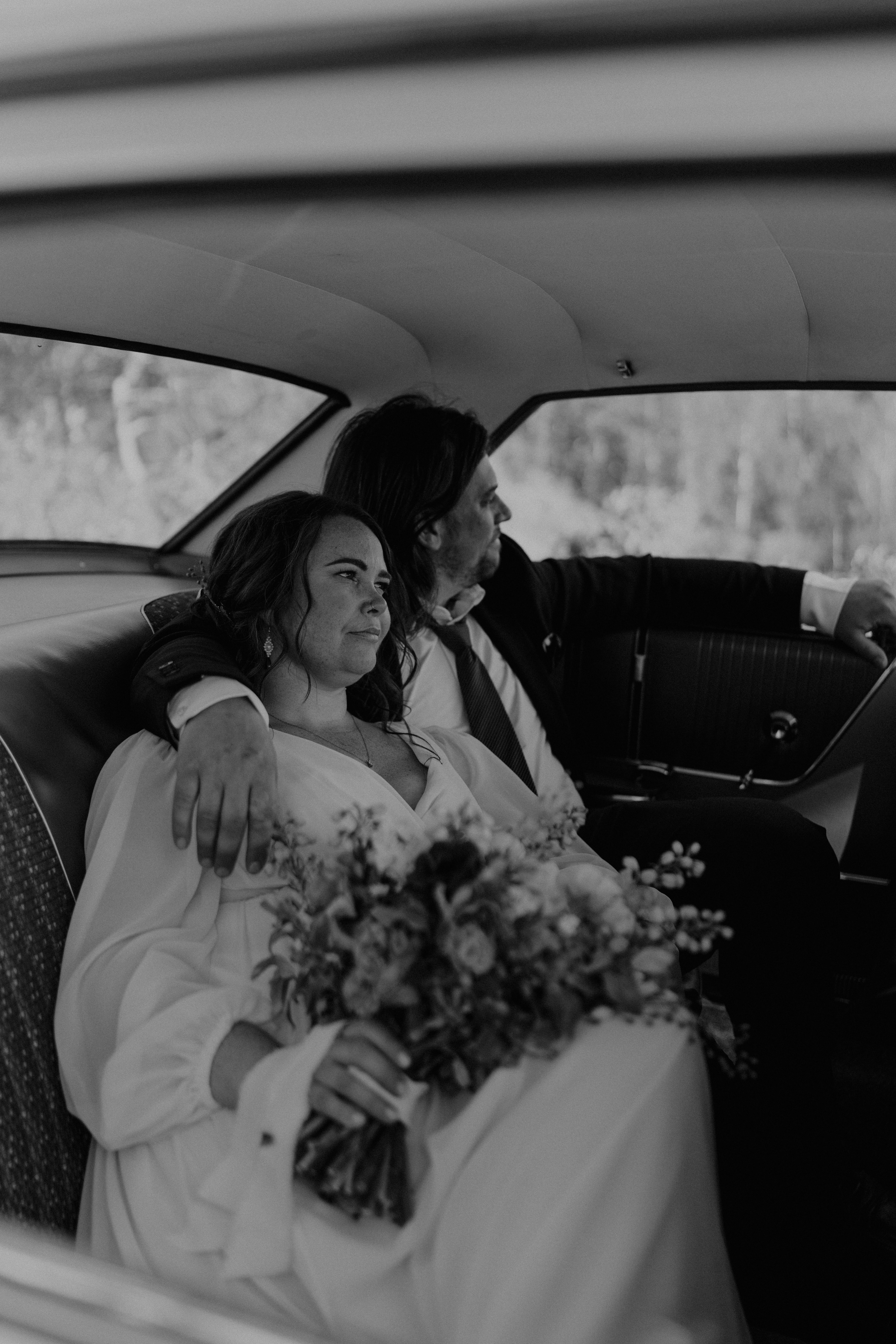 bride and groom sitting in back of classic car