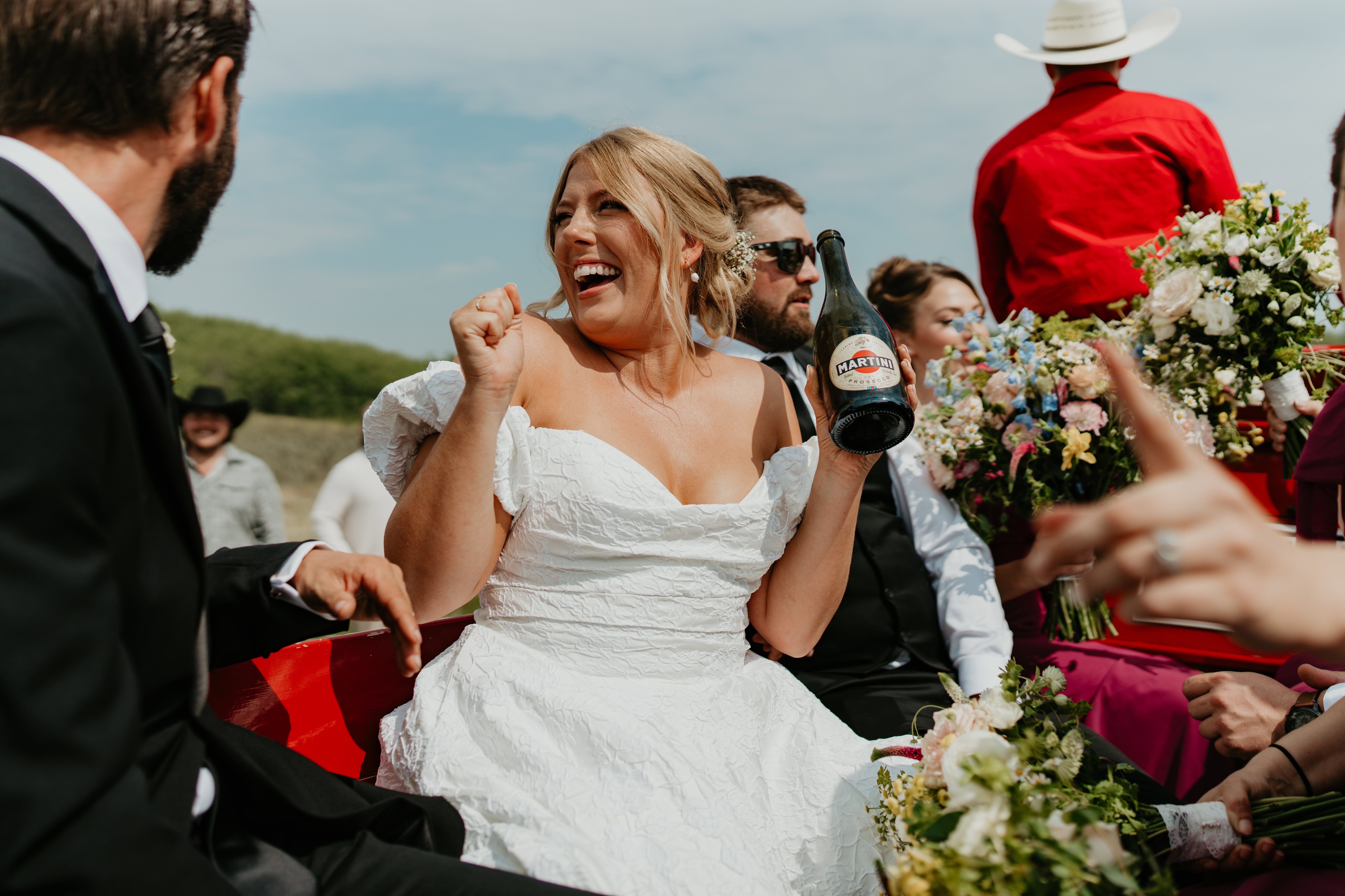 wedding party on wagon, bride celebrating with champagne, candid wedding photos