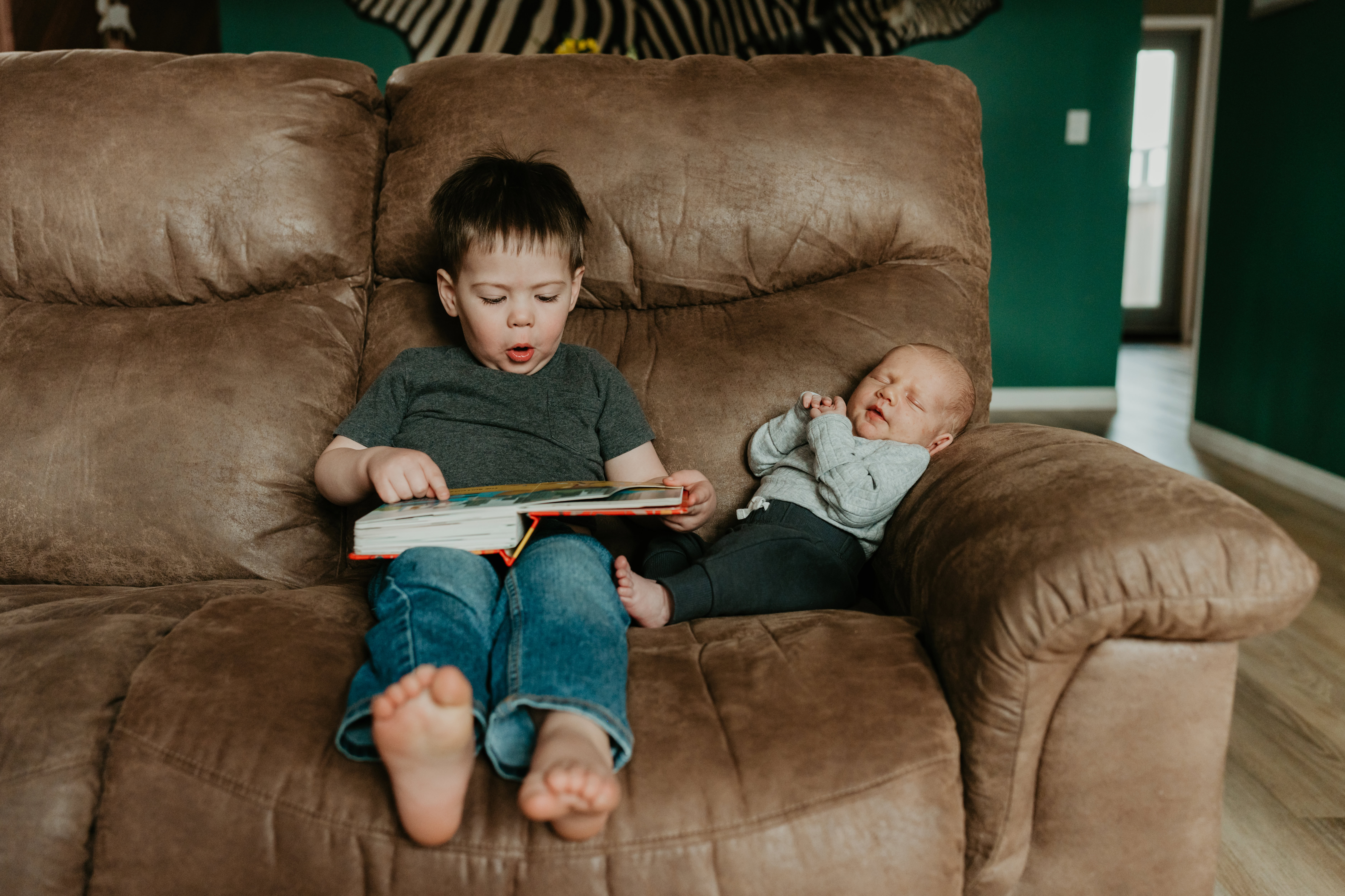candid family photos in home, brother reading baby his book 